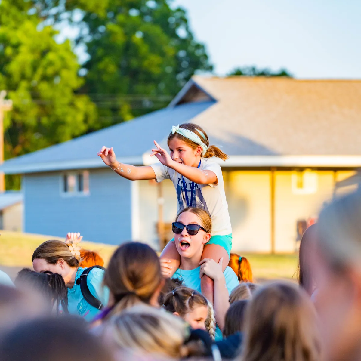 Kids cheering at golden hour during Keystone&rsquo;s summer camp, one child up on a leader&rsquo;s shoulders