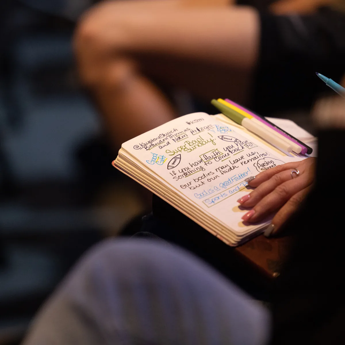 A journal of handwritten sermon notes open across someone&rsquo;s lap during a Keystone service