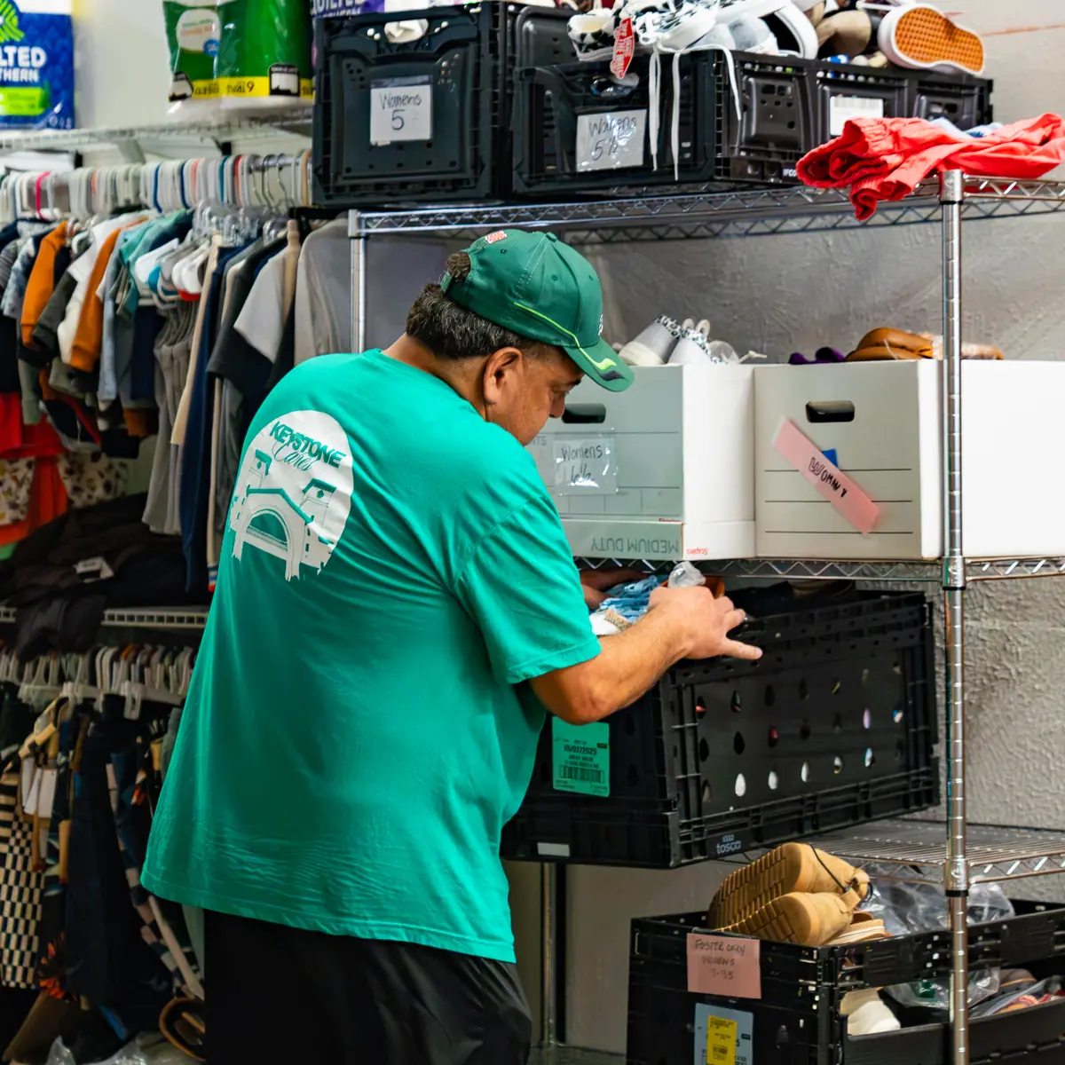 A Keystone Cares volunteer sorting donated clothing on the shelves midweek